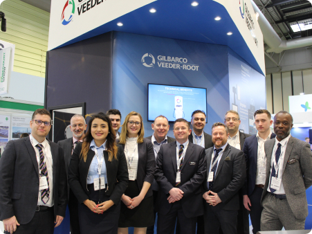 group of people smiling in front of an exhibition stand