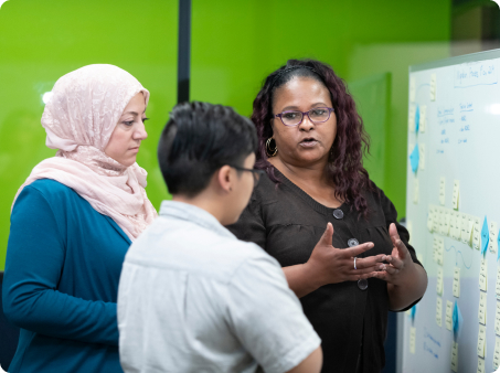 Three people planning using post it notes on a board